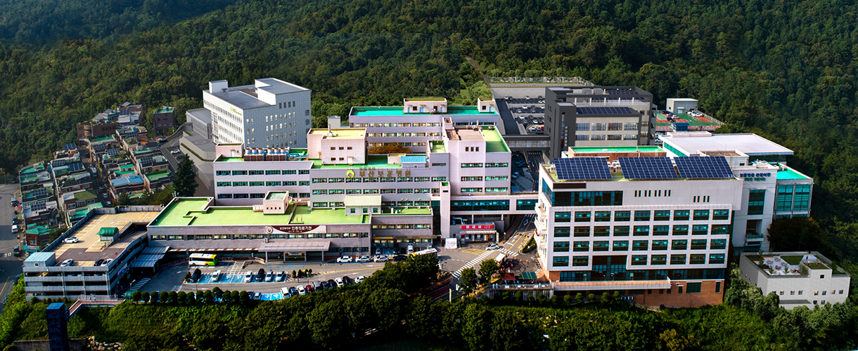 부산보훈병원의 원내 배치도입니다. 산으로 둘러싸인 병원전경 사진, 좌측에는 제 4주차장과  부산요양병원이 있으며, 중앙에는 본관과 그 뒤편으로 별관이 위치합니다. 우측으로는 재활센터과 제 1주차장, 동관, 장례식장이 위치합니다.